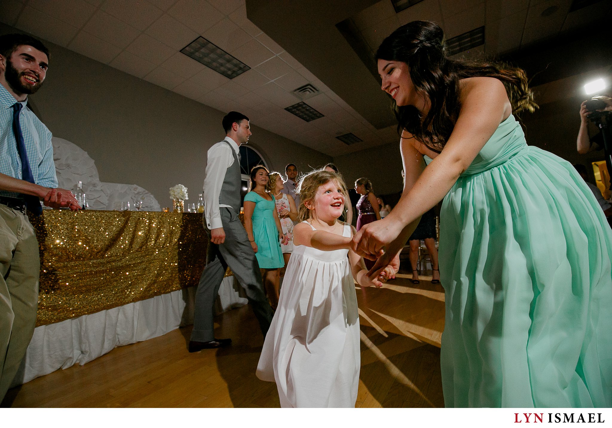 Bridesmaid in mint dress dancing with a flower girl at Alma Community Centre