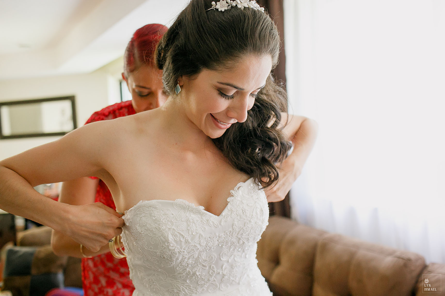 Maid of honour helps the bride get into her dress
