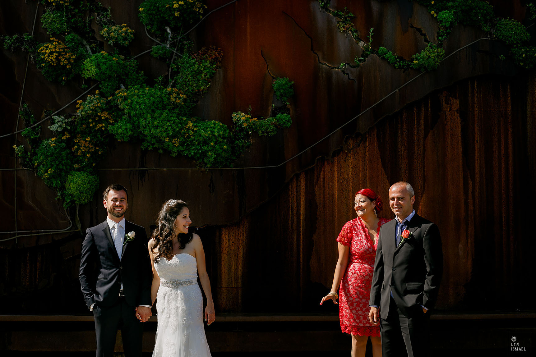 Bride and groom with the Maid of Honour and Best Man standing in harsh light at Ever Green Brick Works