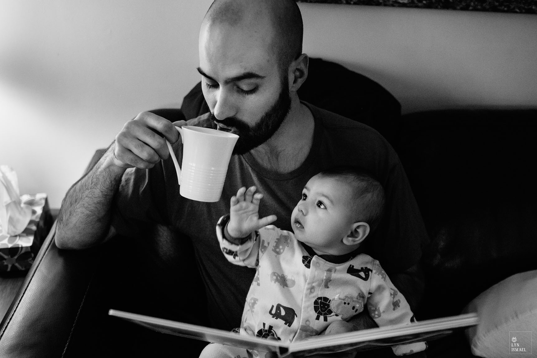 Baby boy watches his father drink coffee at a Day In The Life session by Kitchener family documentary photographer