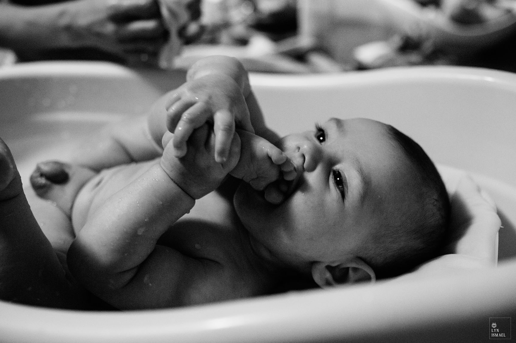 A baby boy sucks his little toes during bath time as photographed by Kitchener family documentary photographer