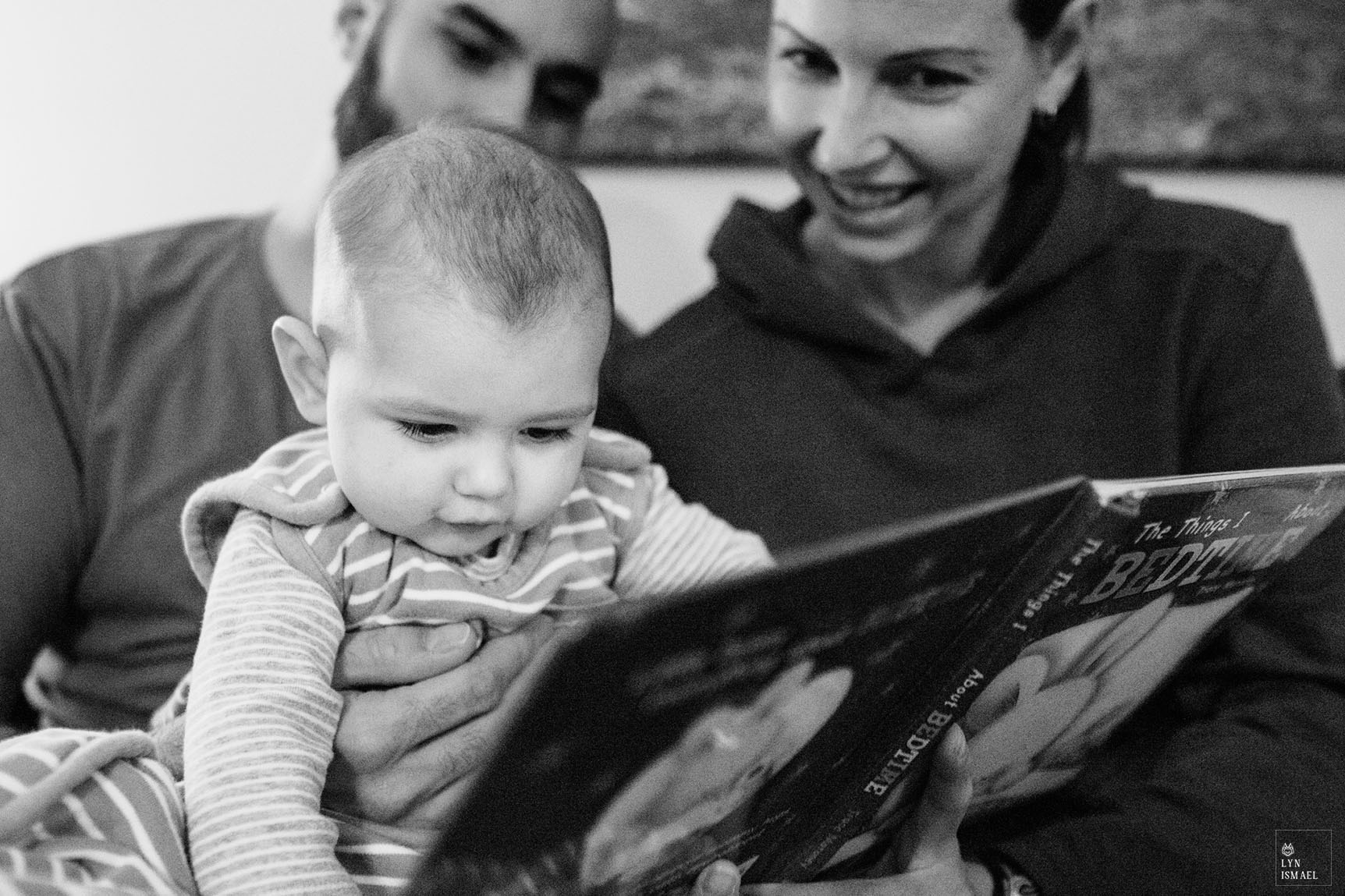 A baby reads a book as photographed by Kitchener family documentary photographer