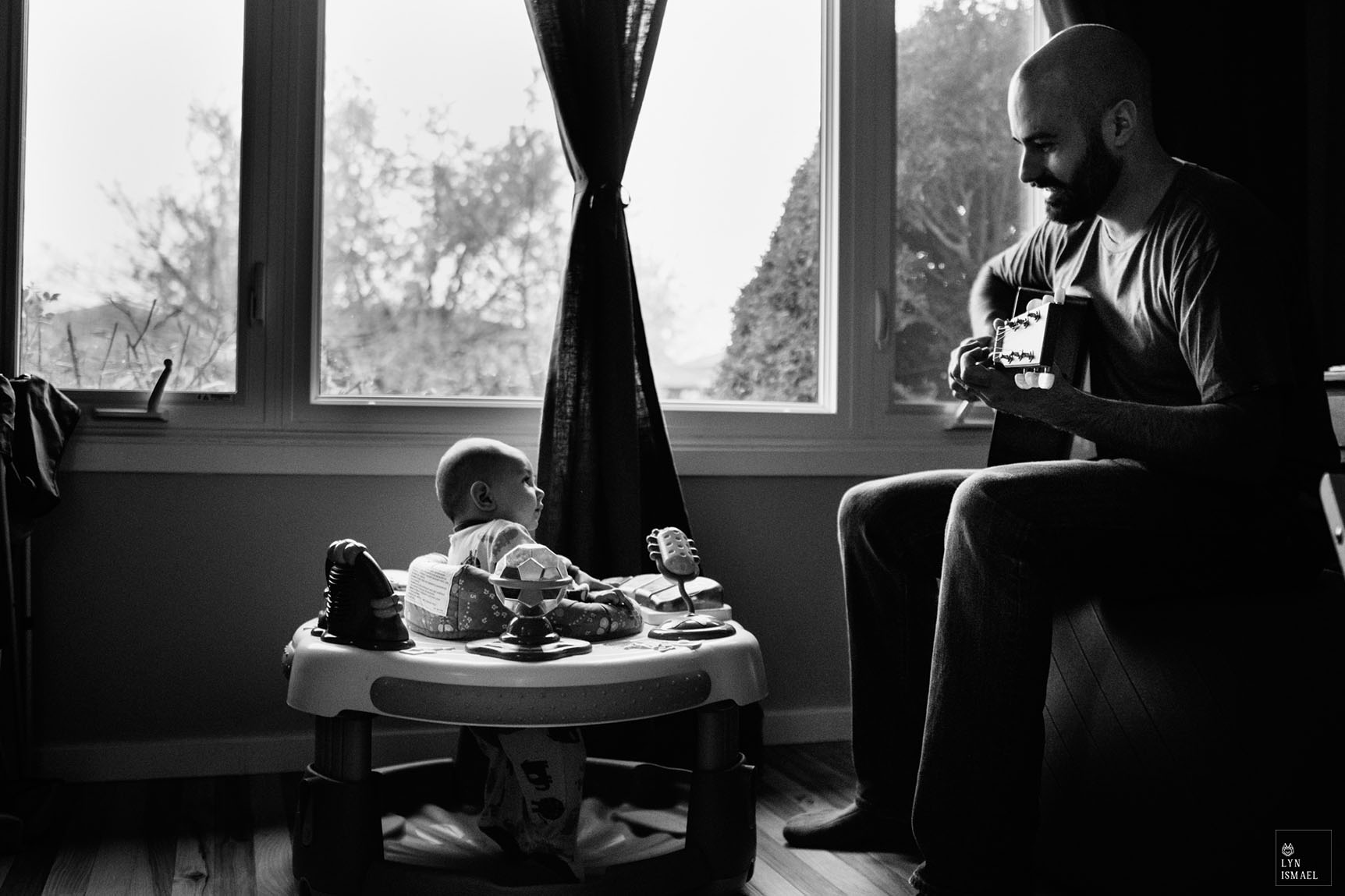 A young father tries to keep his son calm by playing a song as photographed by a Kitchener family documentary photographer