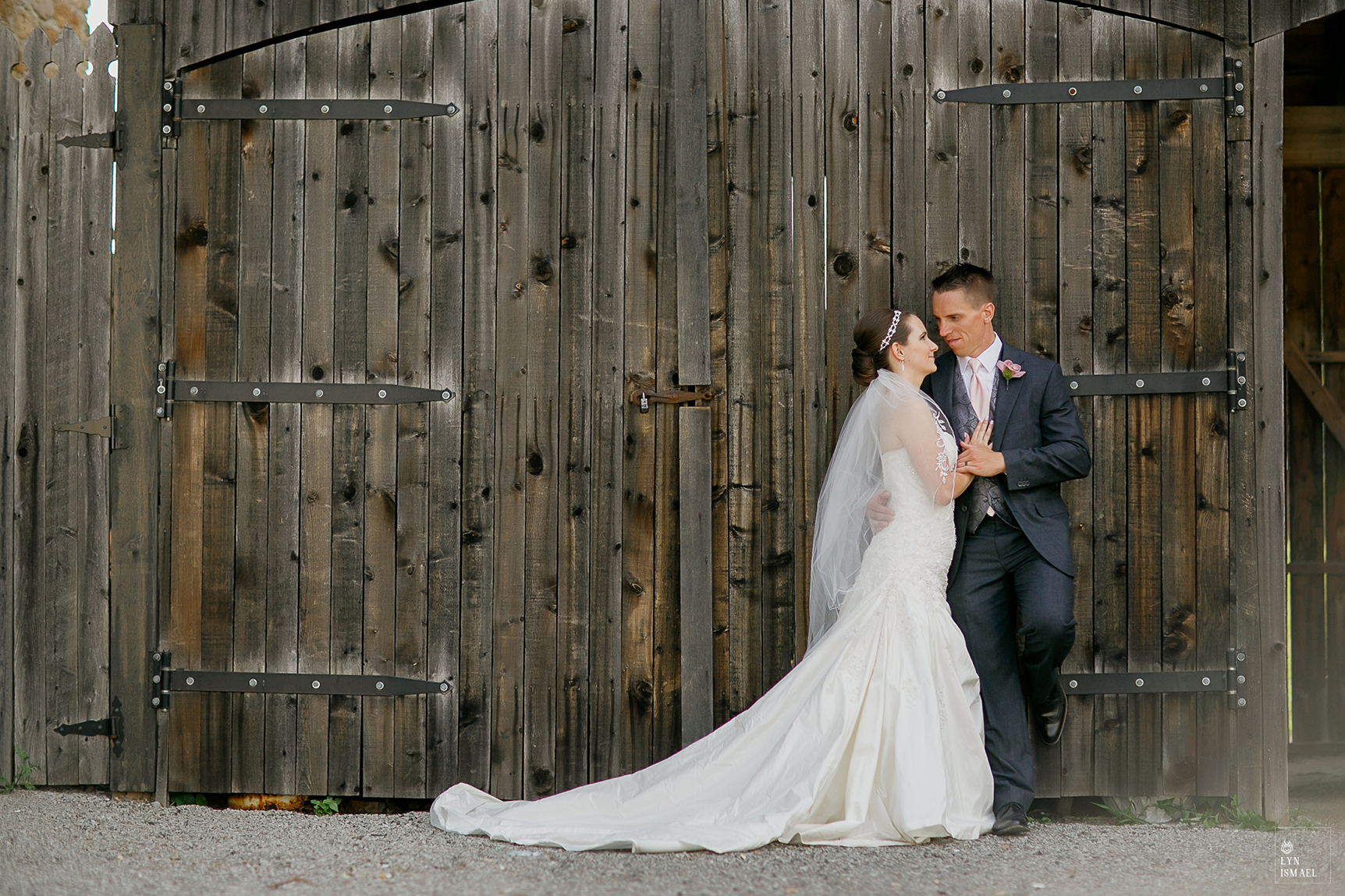 A couple poses in front of the barn located at Dundurn Castle in Hamilton, Ontario.