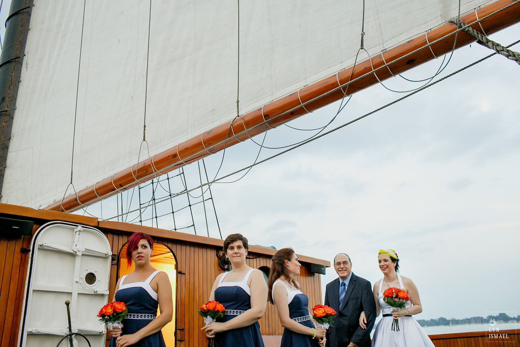 The bride, her father, and her bridesmaids prepare to walk down the aisle on board the tall ship Empire Sandy
