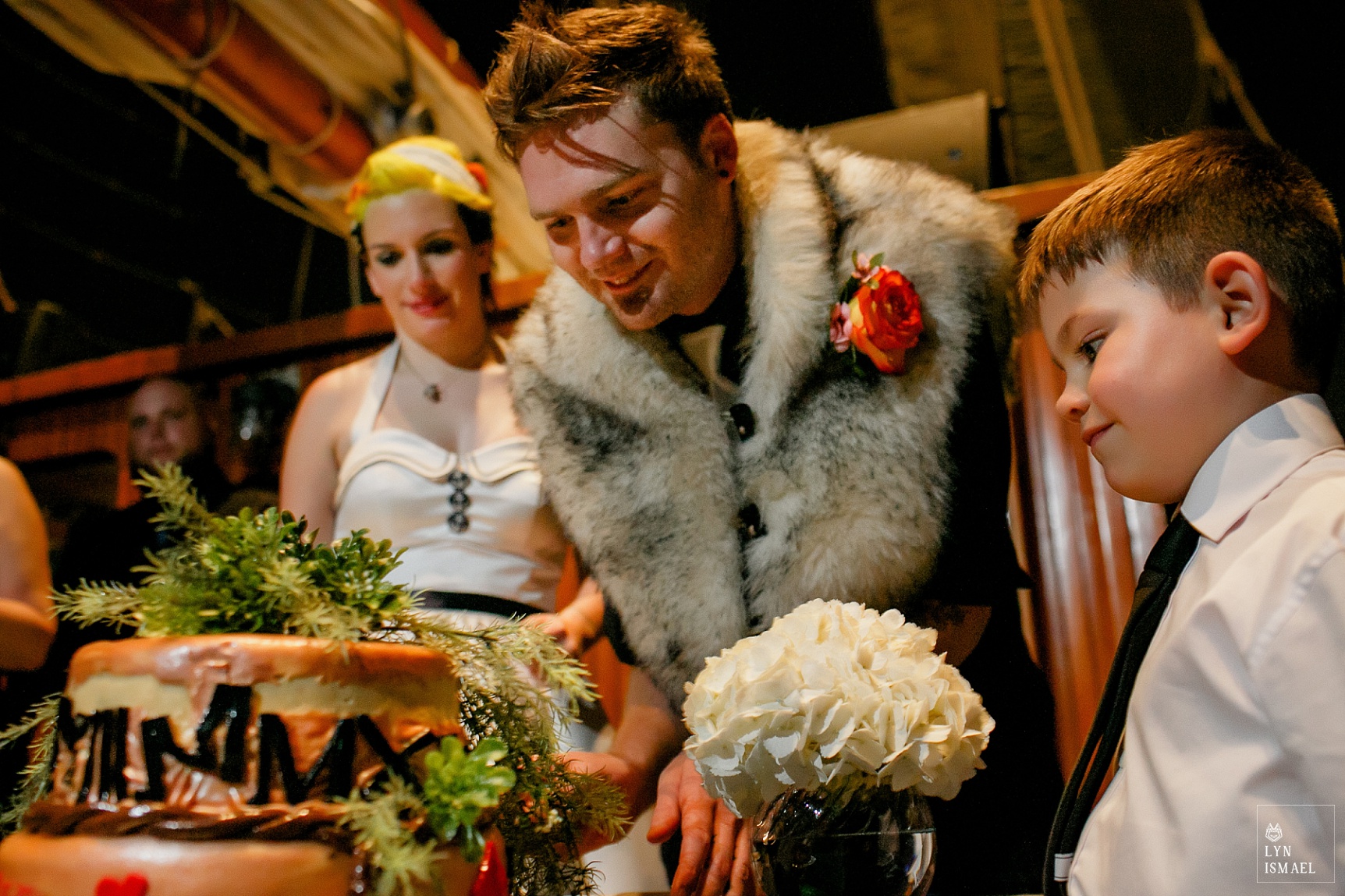 Ringbearer watches as the groom cuts their cake on their nautical themed wedding on the Empire Sandy tall ship based in Toronto.