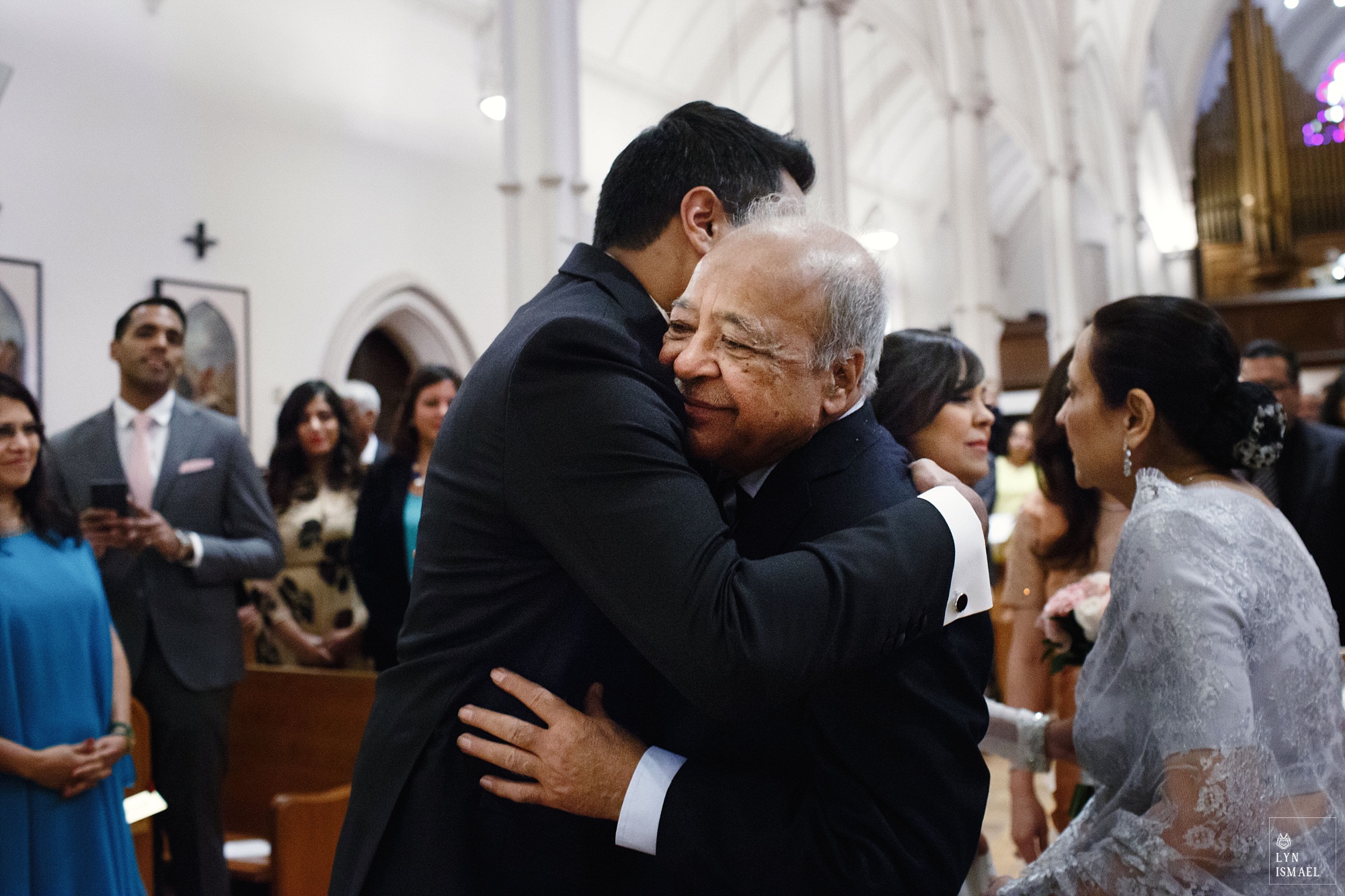 Groom hugs the bride's father at their wedding ceremony at St Basil's Church
