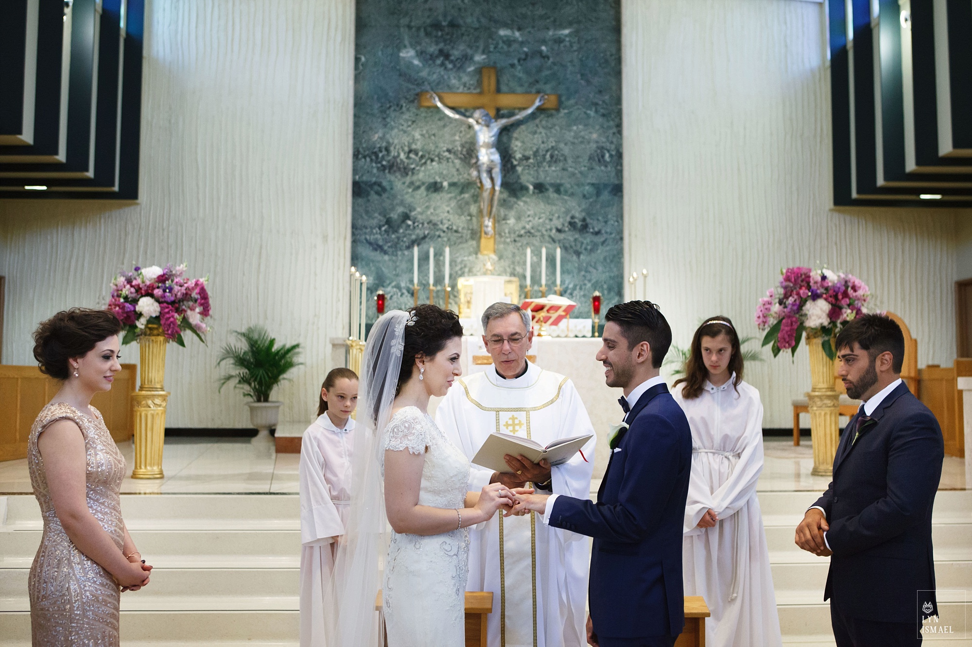 Bride and groom exchange rings at their wedding at St Gregory Catholic Church in Toronto, Ontario.