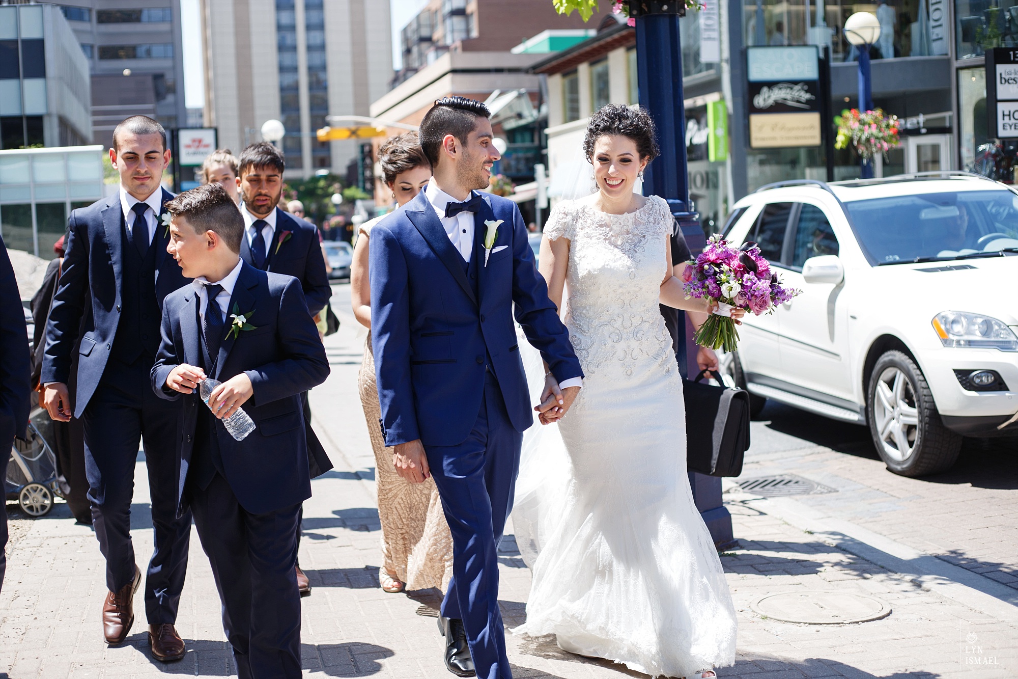 Bride and groom and their wedding party walk down the street of Yorkville in Toronto
